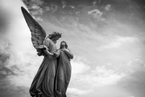 Grayscale photography of angel statue under cloudy skies
