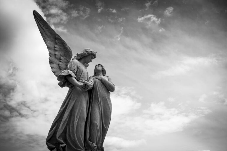 Grayscale photography of angel statue under cloudy skies